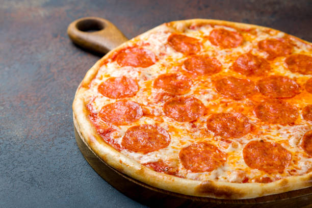 istock Pepperoni pizza on wooden board on blue concrete table macro close up 1410282434