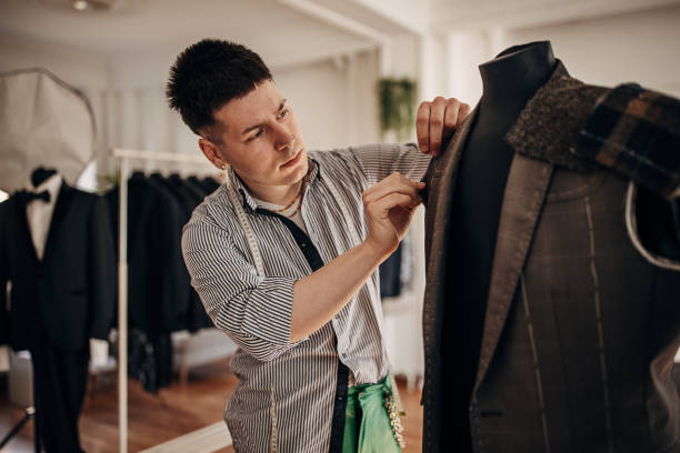 Male fashion designer Male fashion designer making a jacket for a suit in his design clothing studio. luxury craft stock pictures, royalty-free photos & images