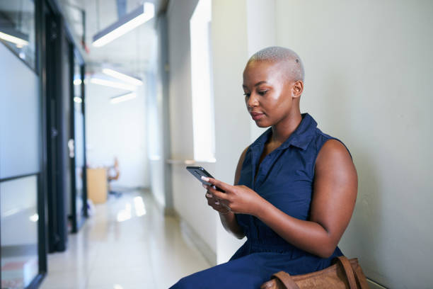 istock A young Black woman texts while sitting and waiting in office corridor 1410285470