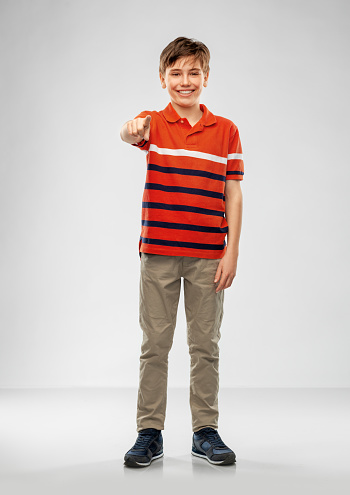 Young pretty boy posing at studio as a fashion model. Photo of a 8 years old kid. Full portrait of boy, isolated.  Portrait of white kid in a red t-shirt and jeans. Boy in a full length