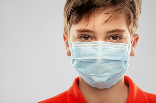 health protection, safety and pandemic concept - close up of boy in protective medical mask over grey background