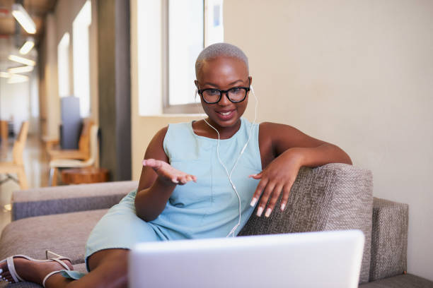 A young Black woman gestures and explains on a conference call in the office A young Black woman gestures and explains on a conference call in the office. High quality photo shaved black women stock pictures, royalty-free photos & images
