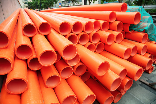 Red plastic water pipes stacked on construction site
