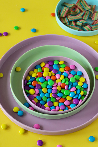 Stock photo of children's rainbow sweets in pastel coloured bowls.