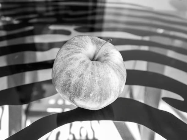 Close-up of apple on abstract wavy stripes background, black and white