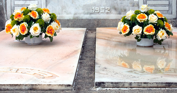 Flower arrangements  in a cemetery. Two multicolored rose flower bouquets on white marble tombstones.  Monterroso, Lugo province, Galicia, Spain.