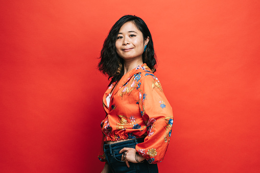 Portrait of confident Japanese woman on red background.