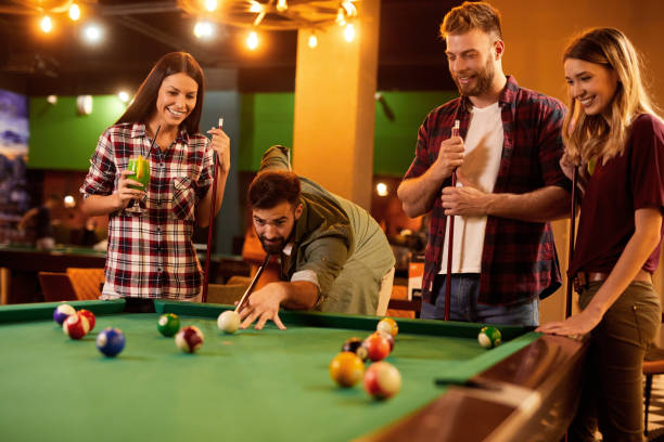 istock Group of friends having fun while playing pool in a local pool hall 1410293773