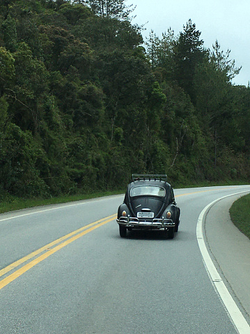 Image with a black antique Beetle classic car on a road trip