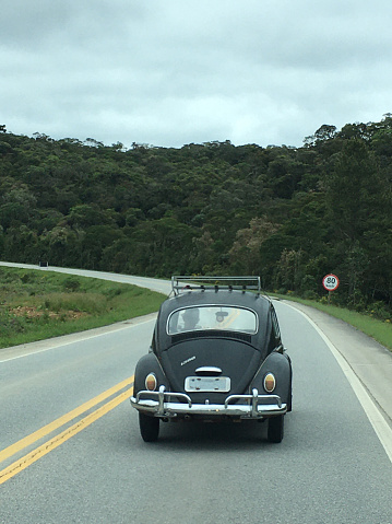 Image with a black antique Beetle classic car on a road trip