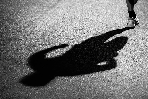 shadow of runner on dark asphalt at night