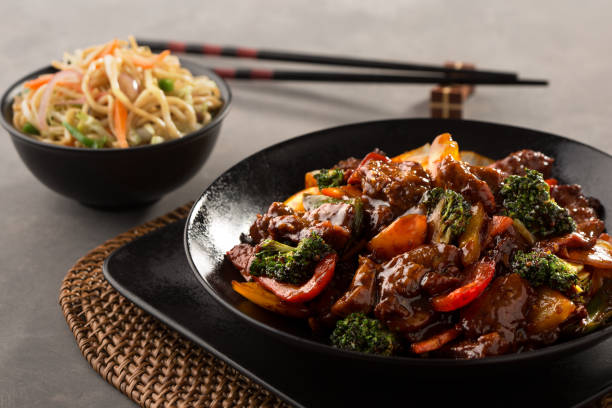 ブロッコリーと炒め麺の牛肉を暗い背景の側面図で隔離した料理で提供 - chopsticks stir fried vegetable beef ストックフォトと画像