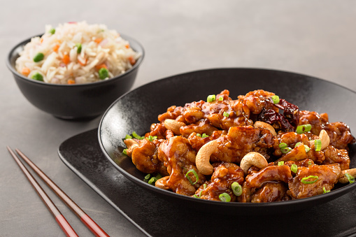 kung pao chicken with chinese rice served in dish isolated on dark background side view