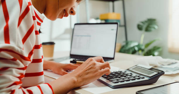 Close-up Young Asian woman with sweater sit front desk with laptop use calculator calculate to utility bills check credit card receipt monthly expense bill at house. Close-up Young Asian woman with sweater sit front desk with laptop use calculator calculate to utility bills check credit card receipt monthly expense bill at house. Home financial lifestyle concept. financial statement stock pictures, royalty-free photos & images