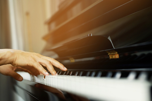close up of hand people man musician playing piano keyboard with selective focus keys. can be used as a background.