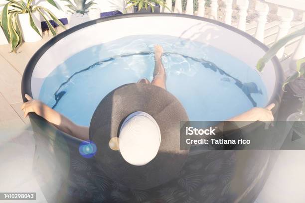 A Woman In A Hat Bathes In A Small Minipool With A Hot Tub With Blue Water On The Roof Of The House In The Sun Against The Backdrop Of Tropical Plants Top View Selective Focus Stock Photo - Download Image Now