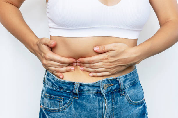 foto recortada de una mujer joven sosteniendo su costado con las manos. dolor en el lado debajo de la costilla - rib cage fotografías e imágenes de stock