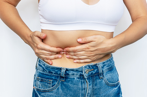 Cropped shot of a young woman in holding her side with her hands isolated on a white background. Sore side under the rib after training. Stomach pain