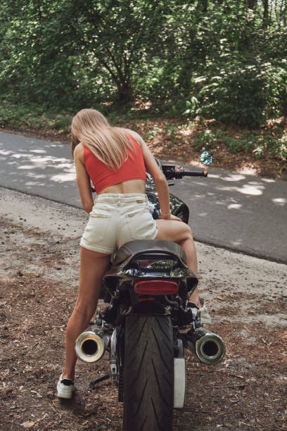 istock Young woman biker drives a motorcycle on a forest road, travels alone 1410299708