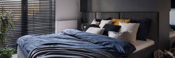 istock Big bed with stylish bedclothes in dark bedroom, panorama 1410299983