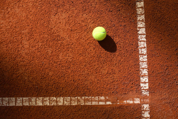 Tennis court Tennis ball on a clay court with lot of copy space. clay court stock pictures, royalty-free photos & images