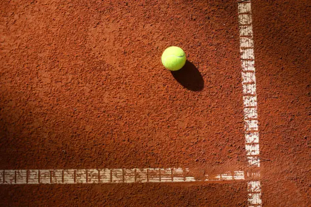 Tennis ball on a clay court with lot of copy space.