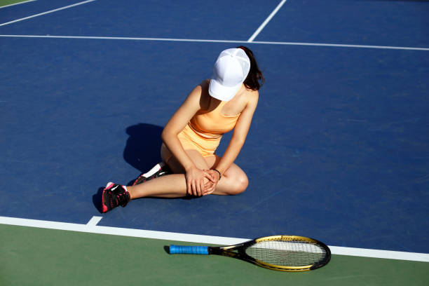 High angle view of happy couple resting during a break from playing tennis on a court and looking at camera. Copy space.