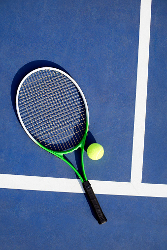 3d rendering a single tennis racquet lying with a yellow ball on white background. Tennis as sport. Tennis as hobby. Tennis classes.