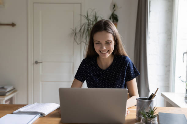 istock Happy student girl sitting at home work table with laptop 1410301574
