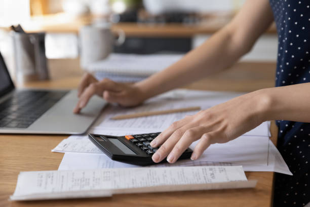 istock Young woman using calculator, laptop for paperwork 1410301691