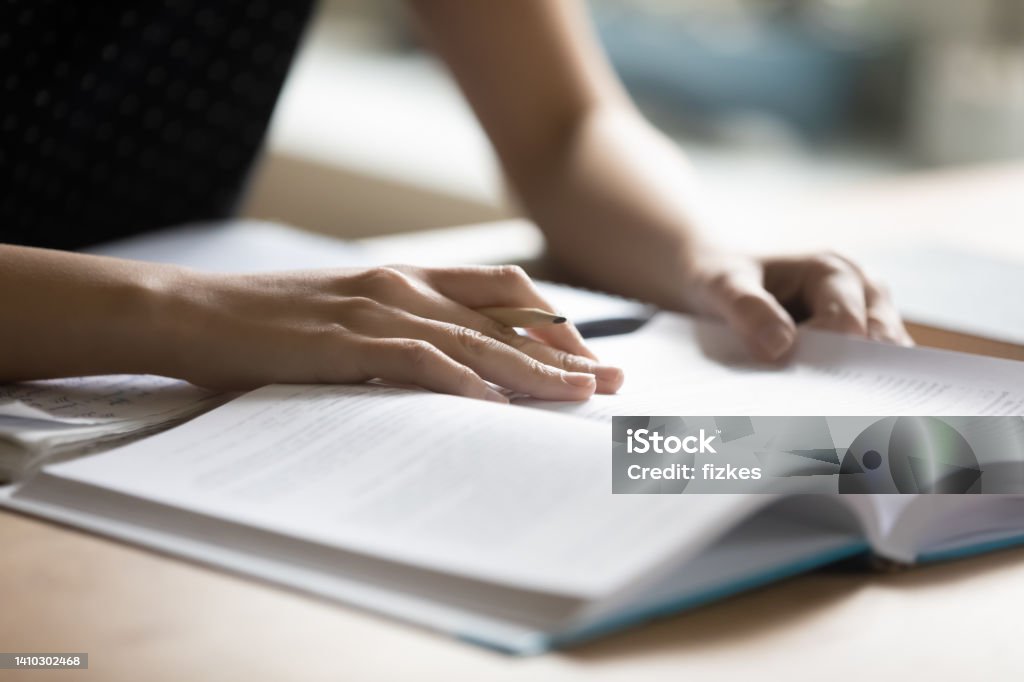 Student preparing for college test, exam, reading book Student preparing for college test, exam, reading book, studying textbook, writing notes, making summary for class report. Learning workplace table, hands with pencil close up Dissertation Stock Photo