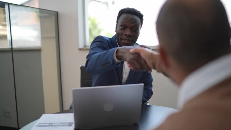 Mature man shaking hands with car salesman while buying a car