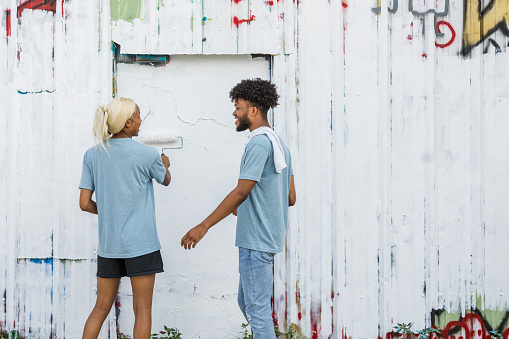 The young adults talk and get to know each other while they volunteer to clean up graffiti.
