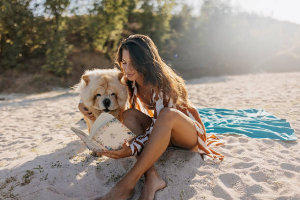 Beautiful woman wearing summer outfit reading to her dog