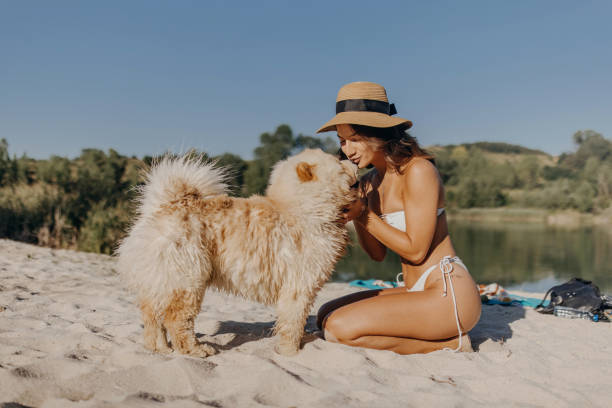 Beautiful woman kissing her dog on the lake beach
