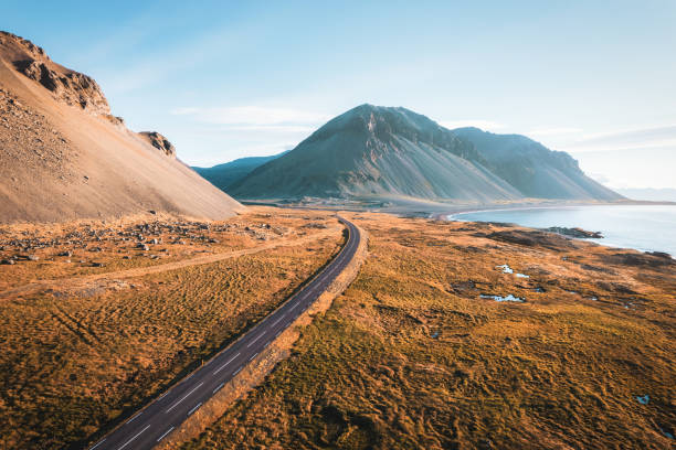 Scenic asphalt road with mountain and golden field on coastline in summer at Iceland stock photo