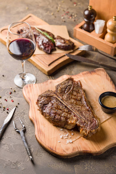 istock Steak T Bone, tibon steak, steak on bone on brown concrete table with red wine, selective focus, vertical 1410306034