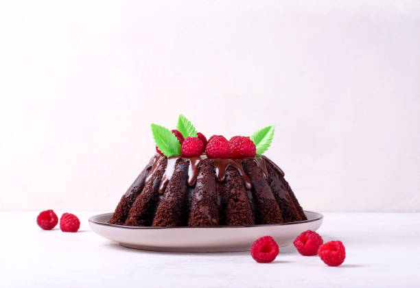 istock Chocolate cake with fluted sides topped with glazing and raspberry 1410309490