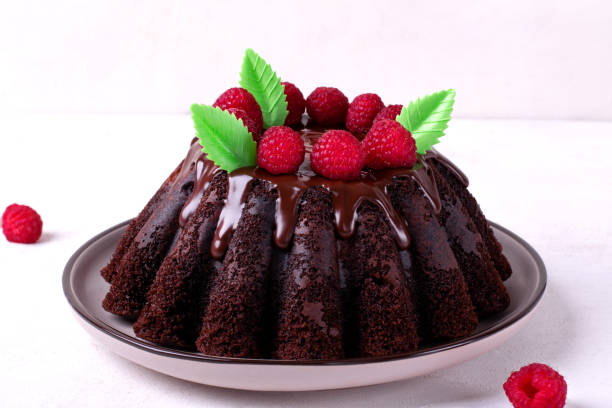 istock Chocolate cake with fluted sides topped with glazing and raspberry 1410309501