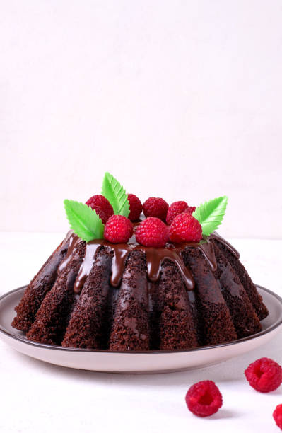 istock Chocolate cake with fluted sides topped with glazing and raspberry 1410310047