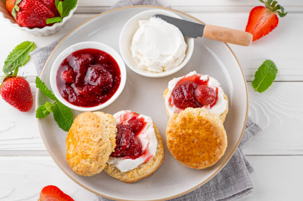 hausgemachte britische scones mit frischkäse, erdbeermarmelade und einer tasse tee auf weißem holzhintergrund. - english breakfast tea stock-fotos und bilder