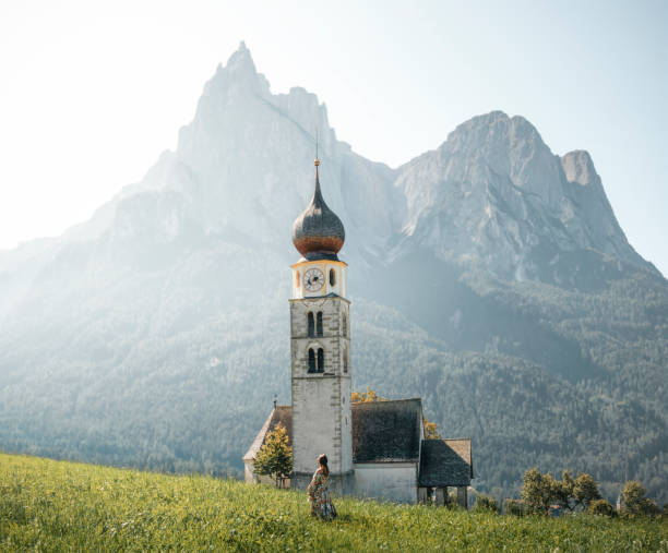 kobieta podróżnik cieszy się wizytą w kościele wiejskim św. walentego (kastelruth) w środku zielonej doliny otoczonej górami włoskich alp w dolomitach - san valentino zdjęcia i obrazy z banku zdjęć