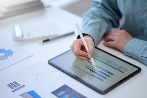 istock Close-up of business woman using tablet analyzing chart and graph showing changes on the market. Female using digital tablet to send text , work or play social media in office. 1410315065