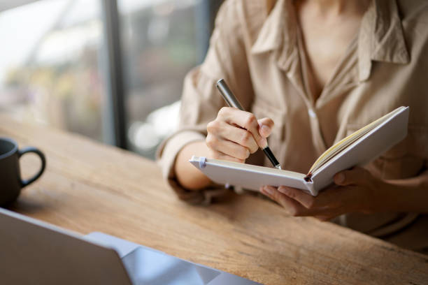 istock Close up image of a woman writing and taking note on notebook with laptop in office. 1410315146