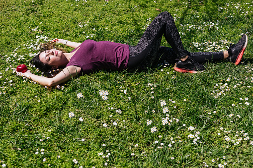 general shot of woman stretched on the grass full of white flowers resting after doing outdoor sports in summer.Japanese daisies.