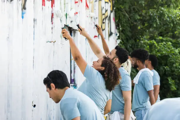 Photo of Diverse group works to paint over graffiti at park