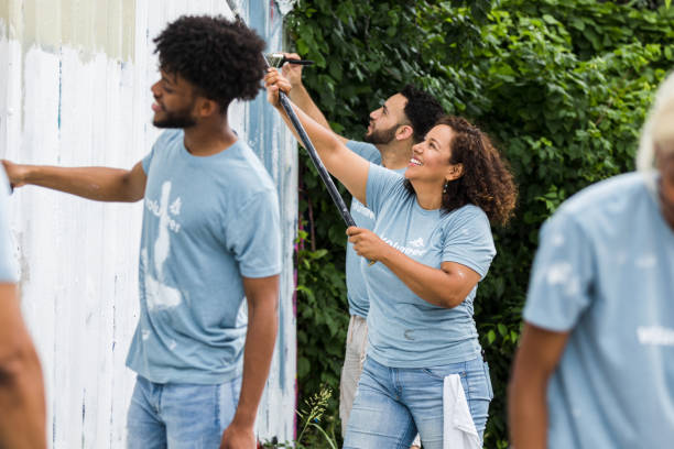 istock Cheerful volunteers roll paint over graffiti covered wall 1410319974