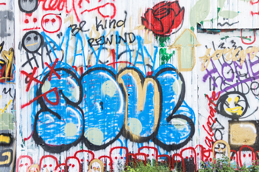 A wall in a neighborhood park covered by colorful graffiti.