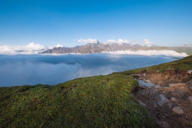 Greater Caucasus mountains covered with evening clouds with Mount Shani 4451m summit. The tourist path going down to Stepantsminda Valley, Georgia.
