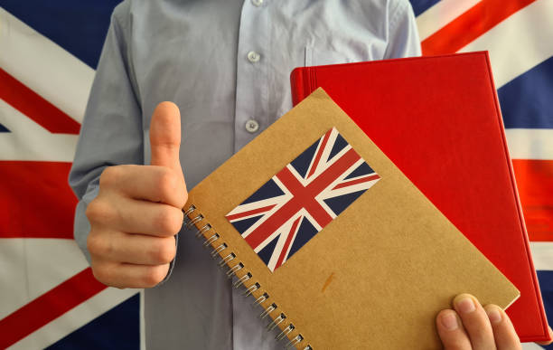 istock Child holds British textbook and thumbs up closeup 1410324512